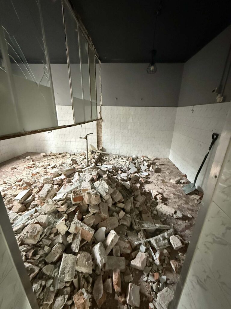 Wyburzona ściana i gruz przygotowany do wyniesienia.