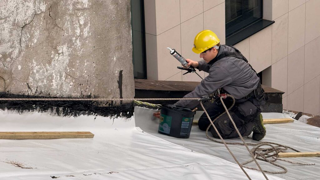 Zabezpieczenie dachu przed warunkami atmosferycznymi przy użyciu plandeki 900g wraz z uszczelnieniem łączeń i krawędzi.